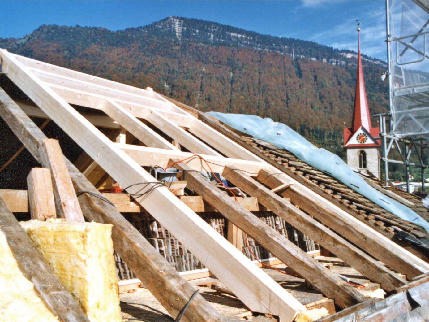 Die zwei Aus­schnitte der neuen Dach­fenster auf der Südseite sind schon gut zu erkennen. Da im Herbst das Wetter oft unsicher ist, musste etap­penweise, Seite für Seite das Dach neu erstellt wer­den. 