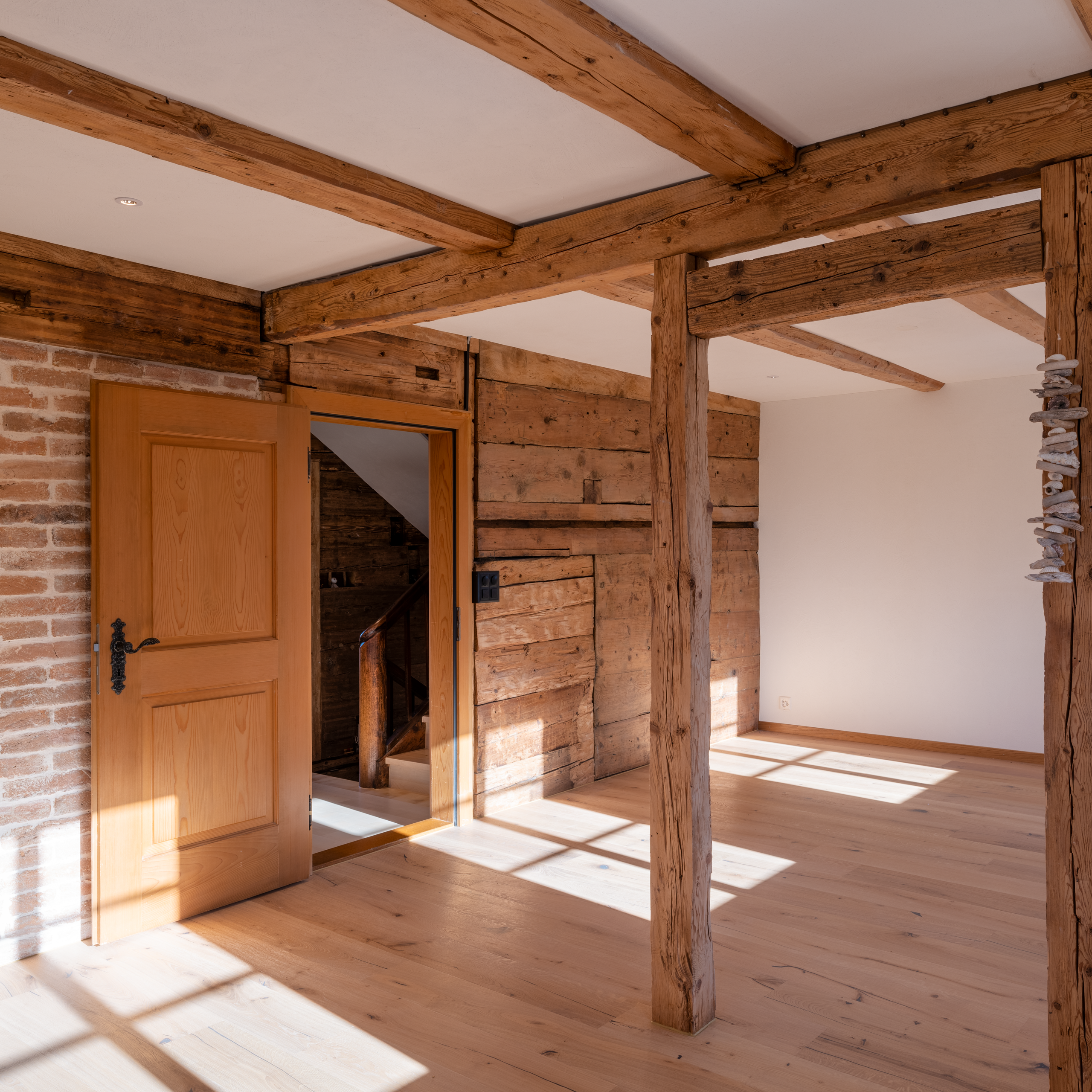 Doppelzimmer im Obergeschoss: gedämmte Aussenwände mit Wandheizung und Sumpfkalkputz sowie freigelegtes Holzwerk.